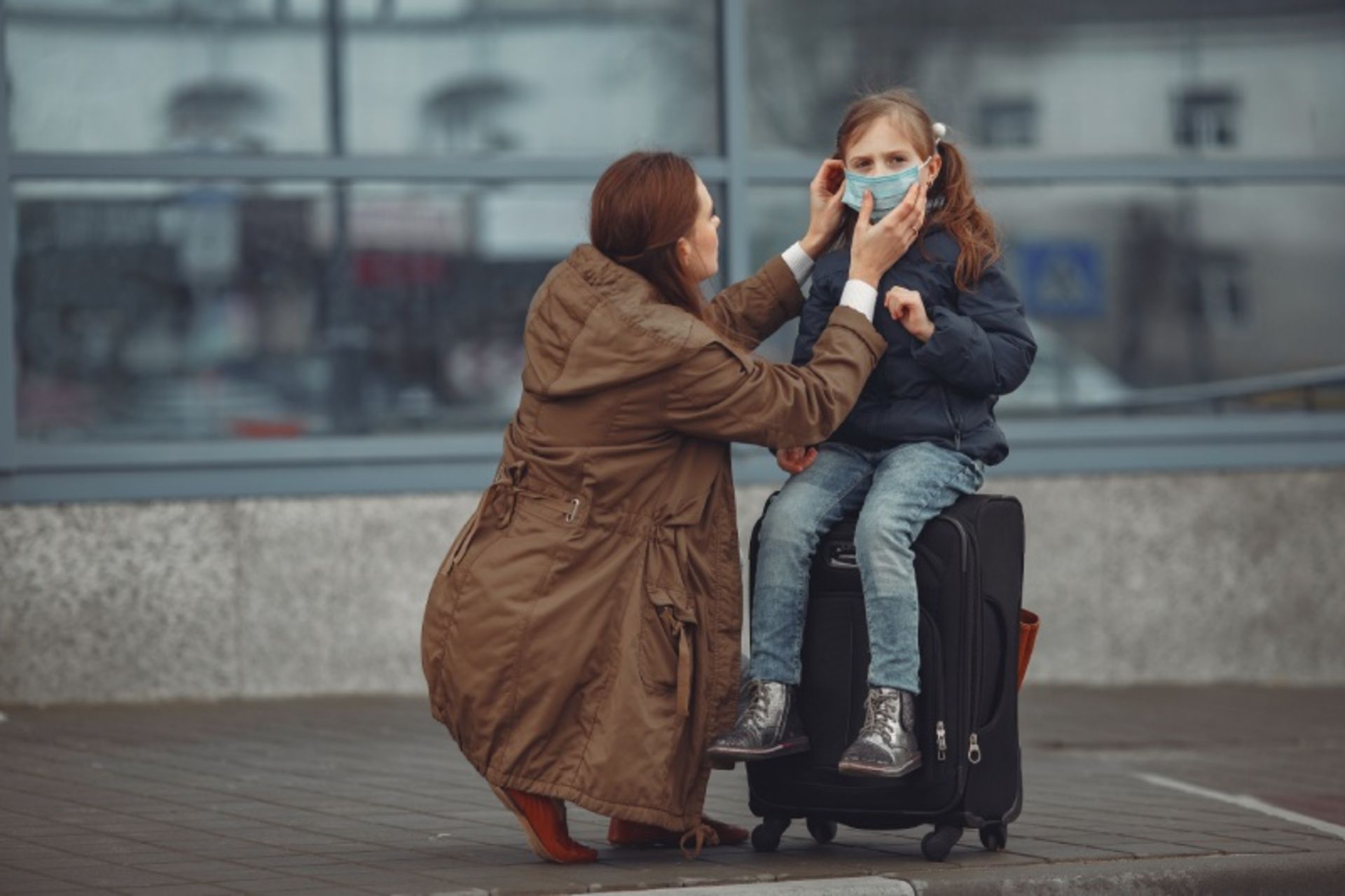 مادری با لباس قهوه ای و دختربچه ای با چمدان سفر
