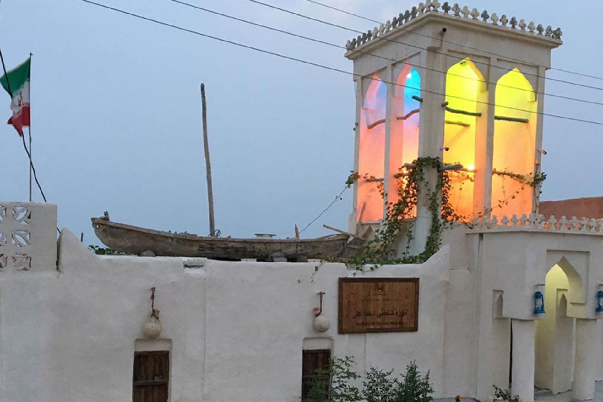 بادگیر ساختمان سنتی با نور چراغ در غروب آفتاب