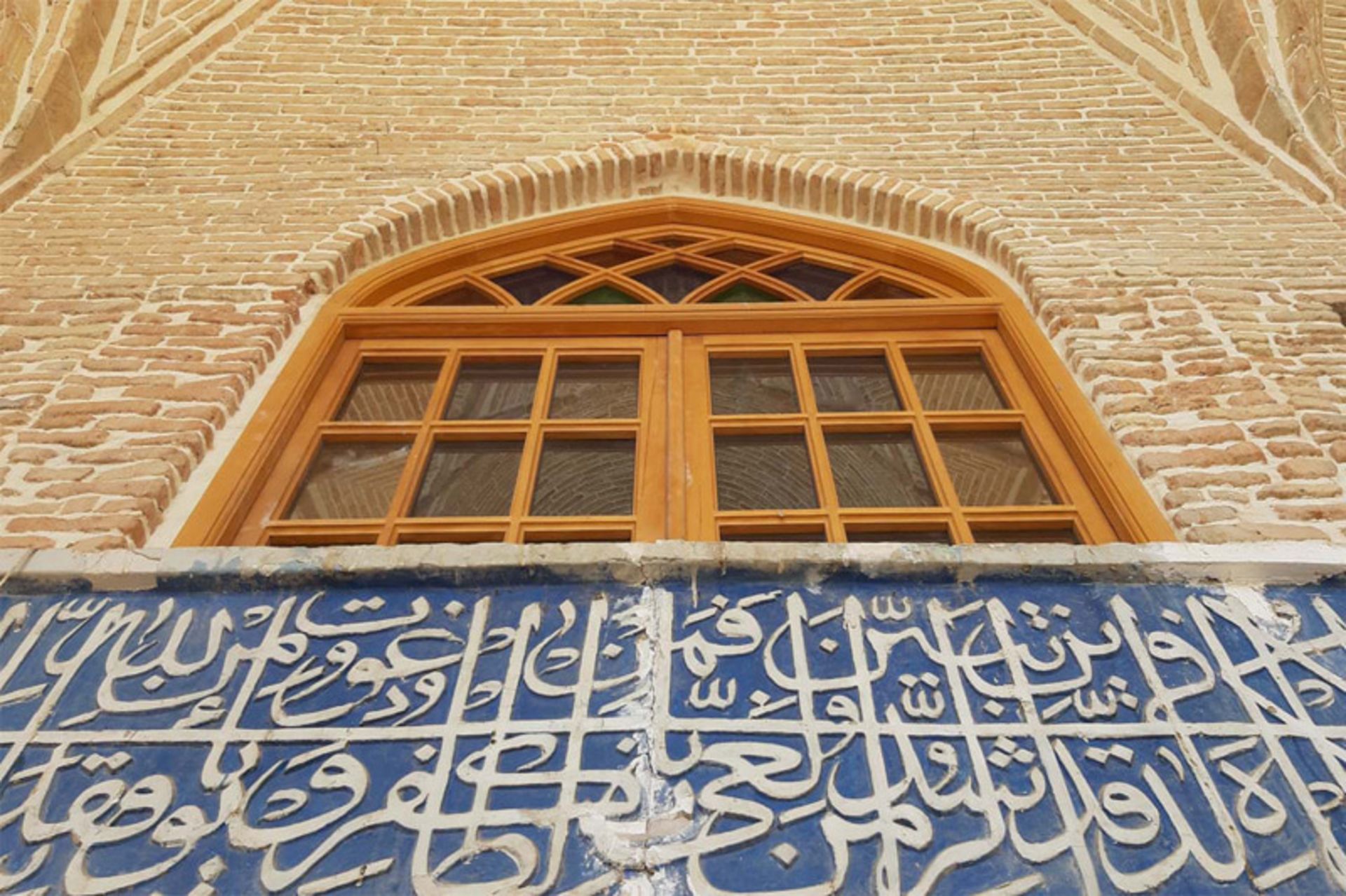 پنجره چوبی و دیوار کاشی کاری  و خطاطی شده