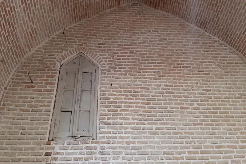 پنجره چوبی بر دیوار آجری مسجد