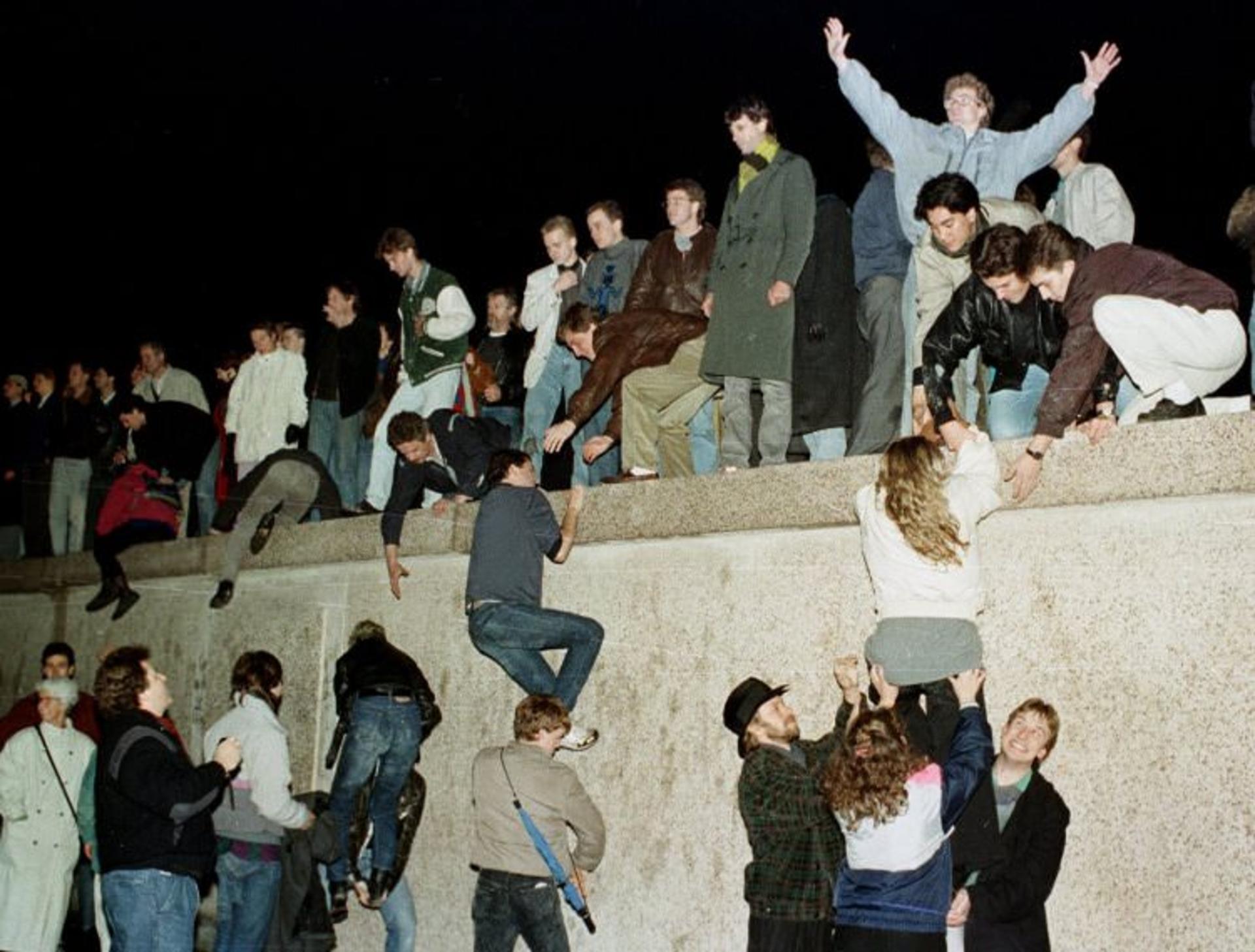 2015-11-east-germans-celebrated-as-they-climbed-the-berlin-wall-at-the-brandenburg-gate