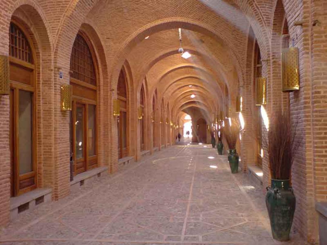 راهرویی با دیوارهای آجری و درهای چوبی در سرای سعد السلطنه قزوین