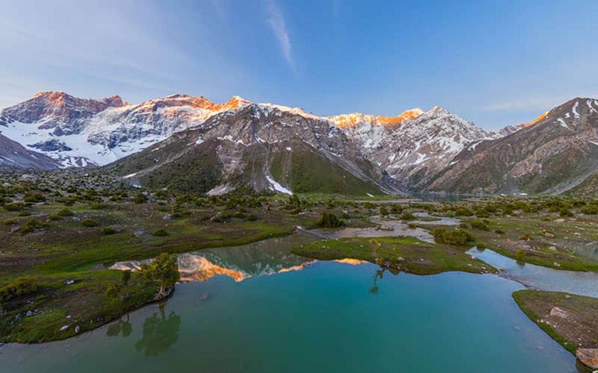 دریاچه ای در کنار کوهستان و انعکاس کوهها در آب