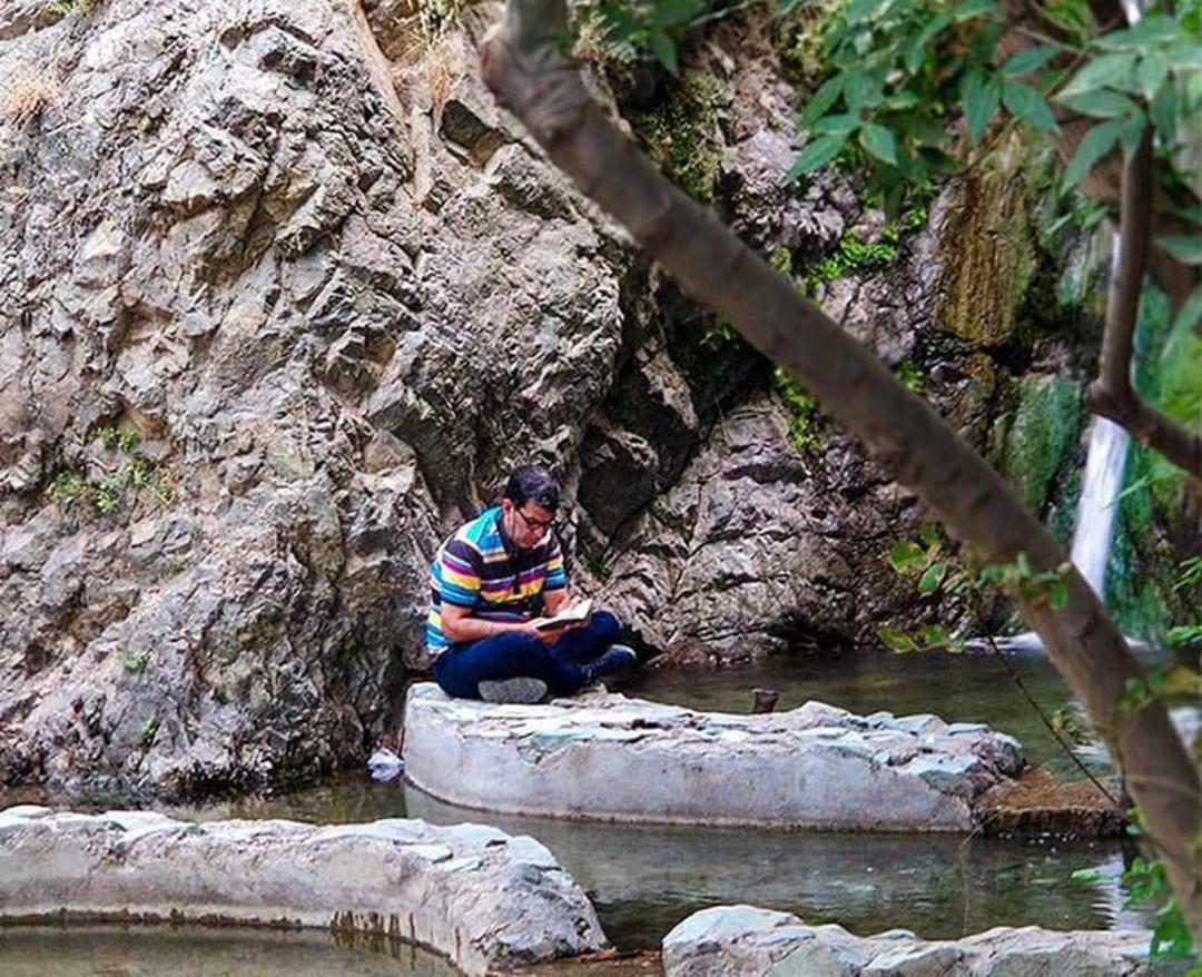 مردی در کنار آبشار و صخره
