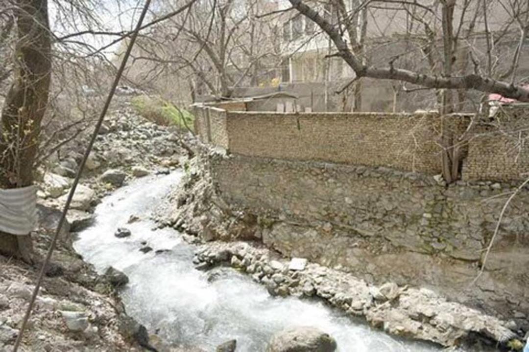 رودخانه درکه کنار دیوار آجری در مسیر کوهستان