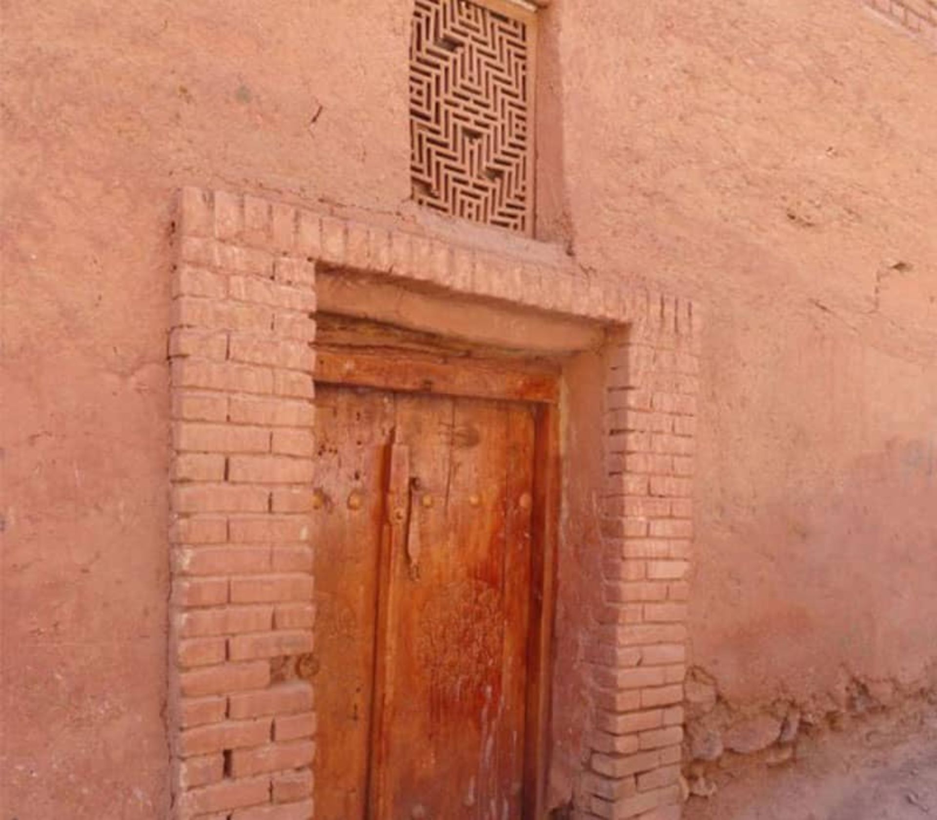 در چوبی قدیمی با پنجره ای مشبک در بالای آن