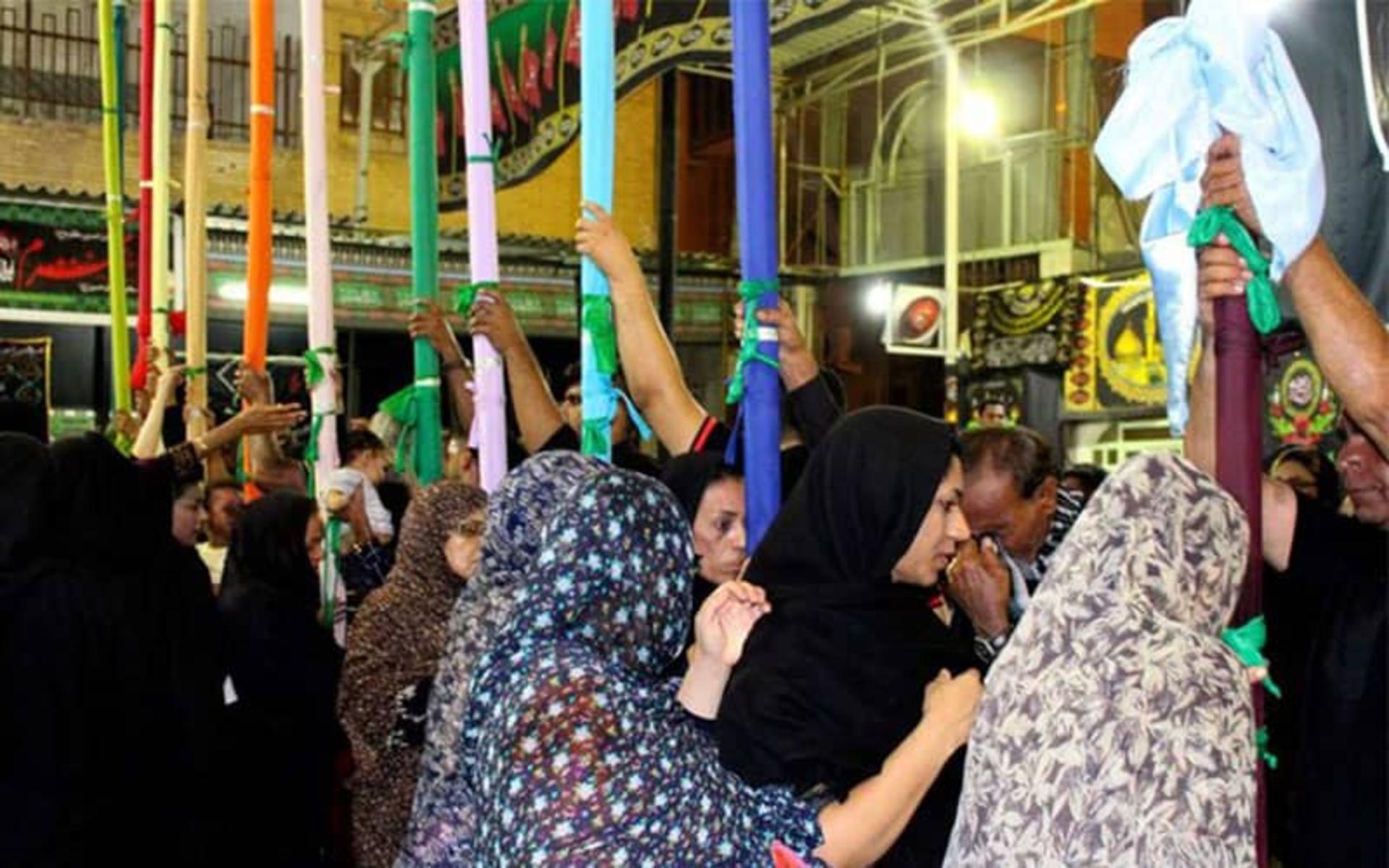 زنان عزادار در حال تزیین علم های چوبی