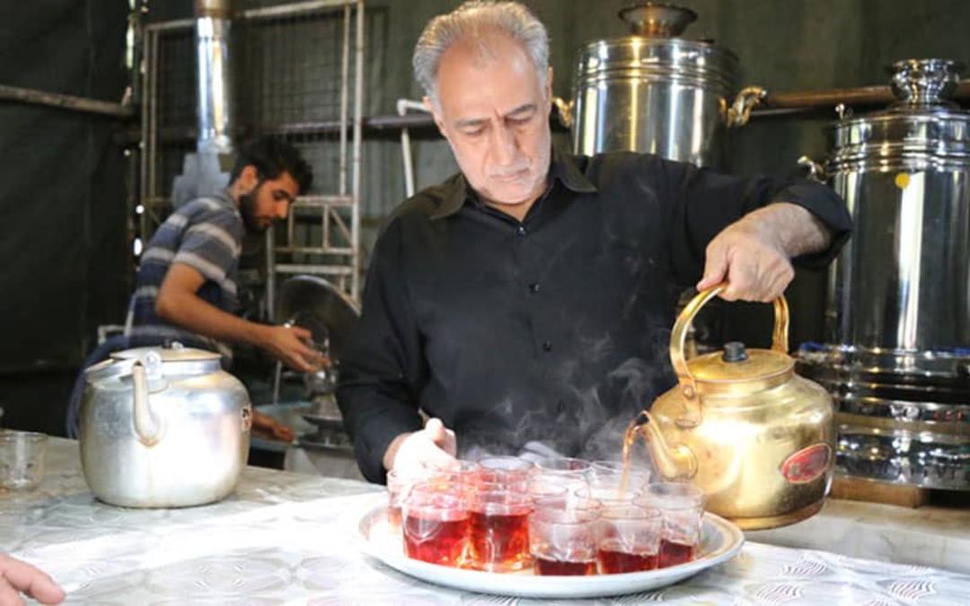 پیرمردی در حال ریختن چای در استکان ها