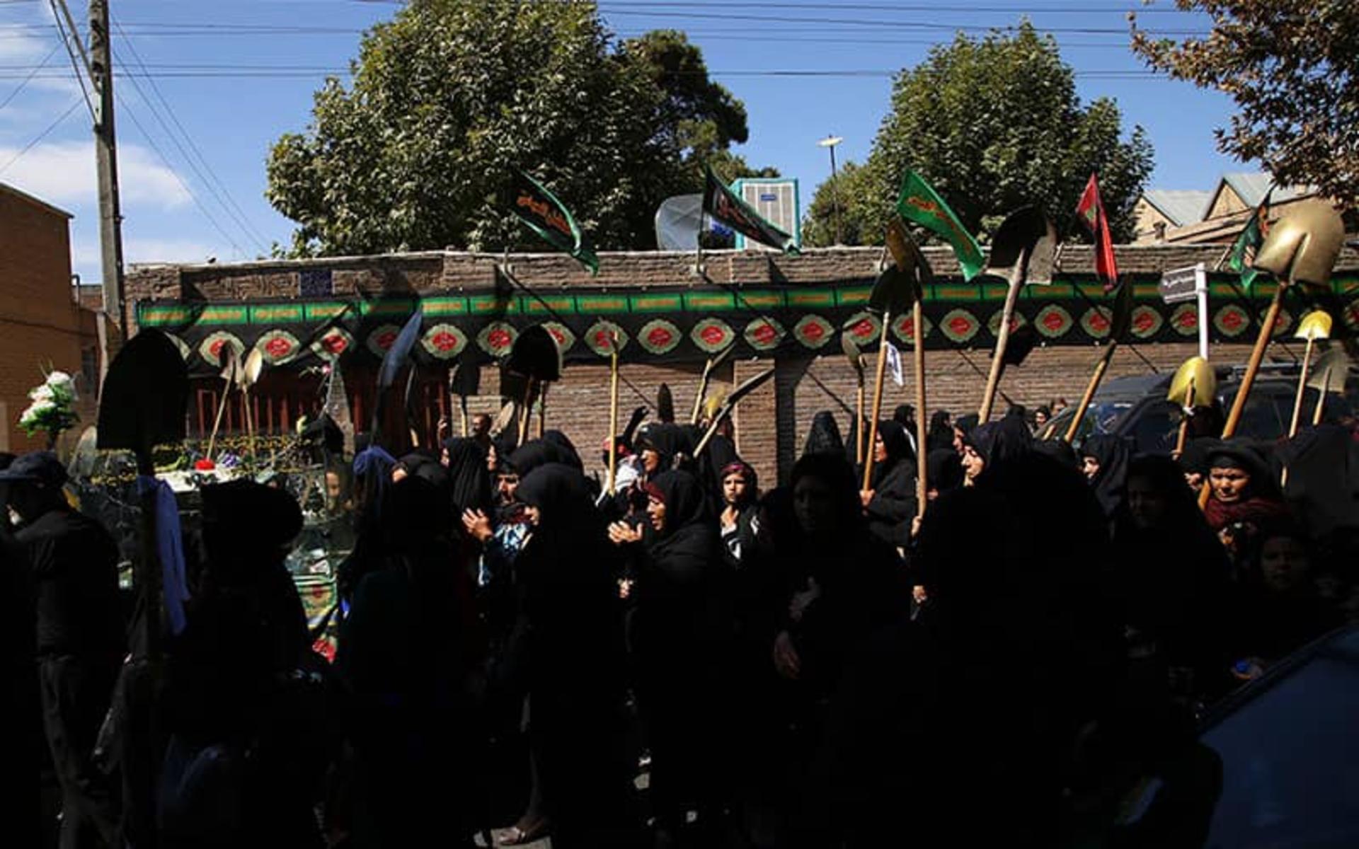 زنان با چادر سیاه و بیل هایی در دست