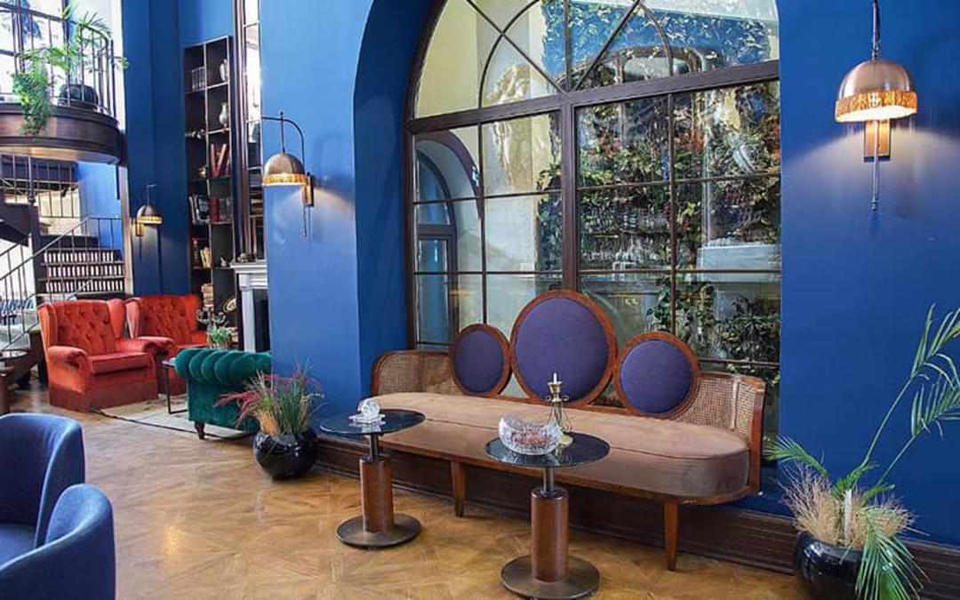 سالن بزرگی به رنگ آبی با مبلمان رنگی و پنجره های بزرگ