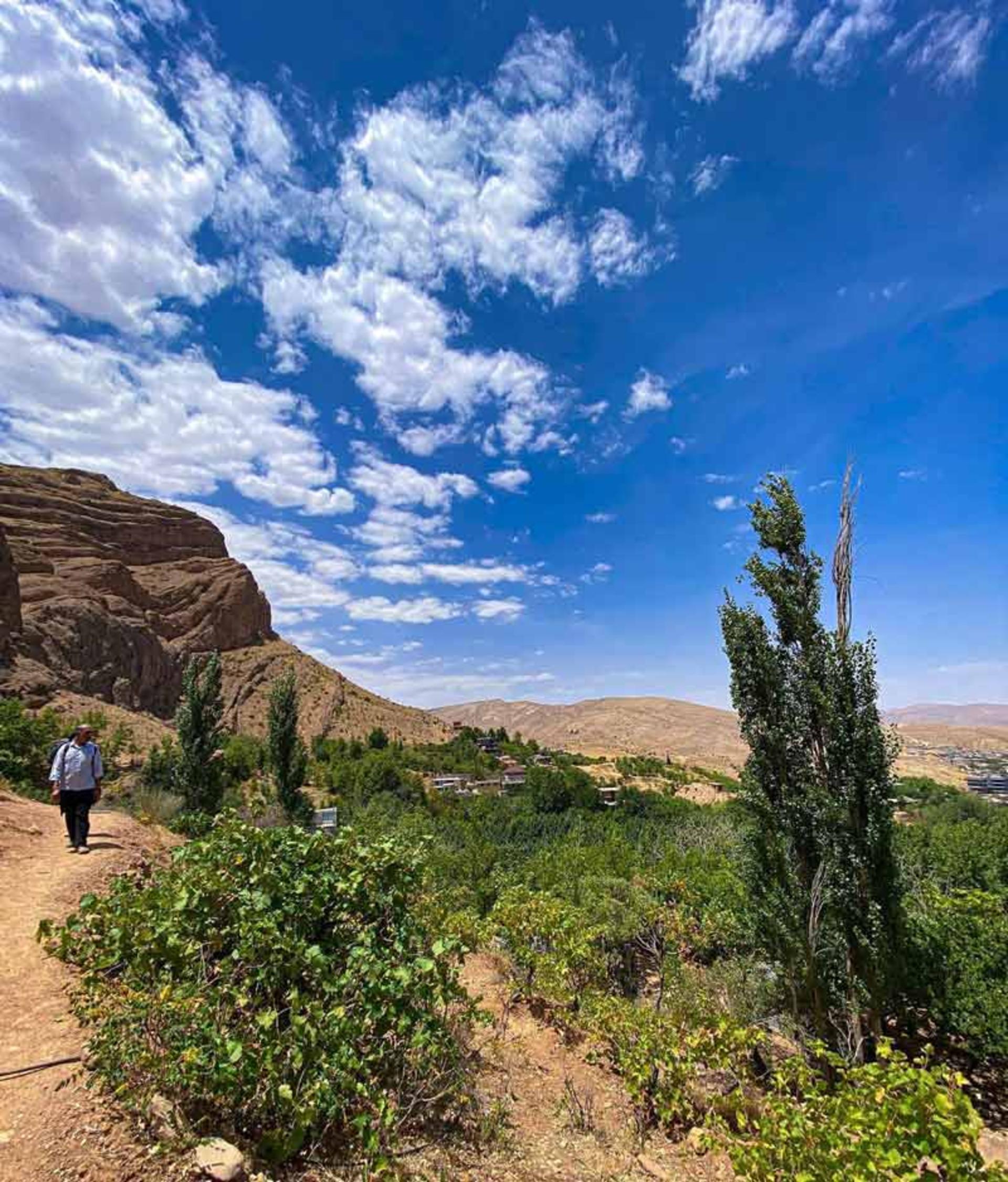 جاده خاکی روستای قلات با درختان سبز زیر آسمان آبی