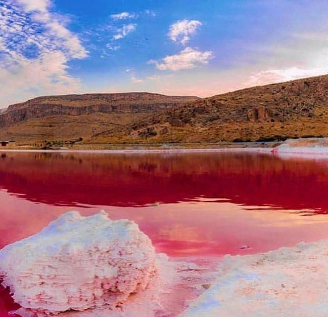 دریاچه سرخ مهارلو با نمک سفید زیر آسمان آبی در جوار کوه