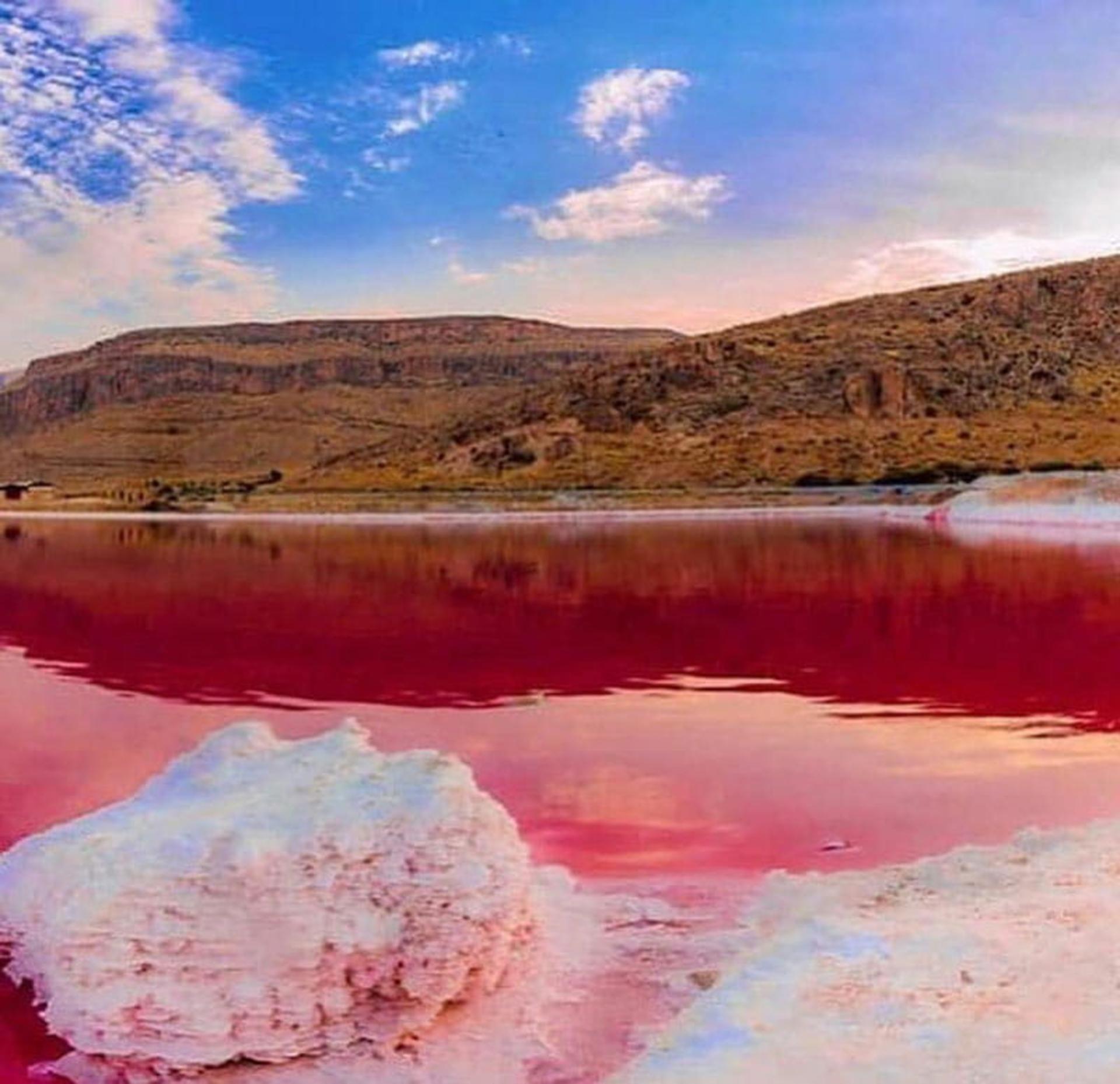 دریاچه سرخ مهارلو با نمک سفید زیر آسمان آبی در جوار کوه