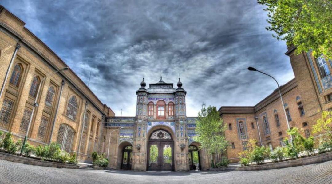 نمایی از ورودی میدان مشق و سردر باغ ملی زیر آسمان پر ابر
