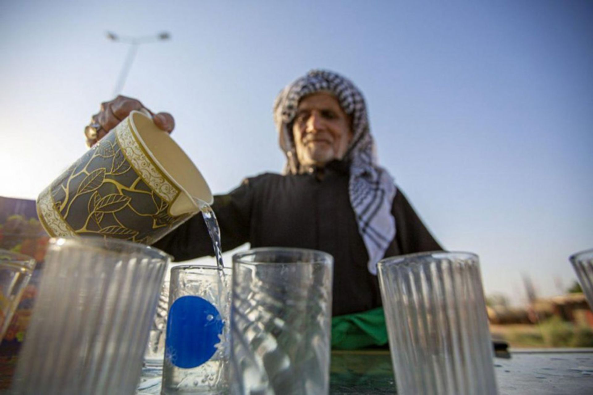 پیرمرد عراقی در حال پذیرایی از زائران پیاده روی اربعین