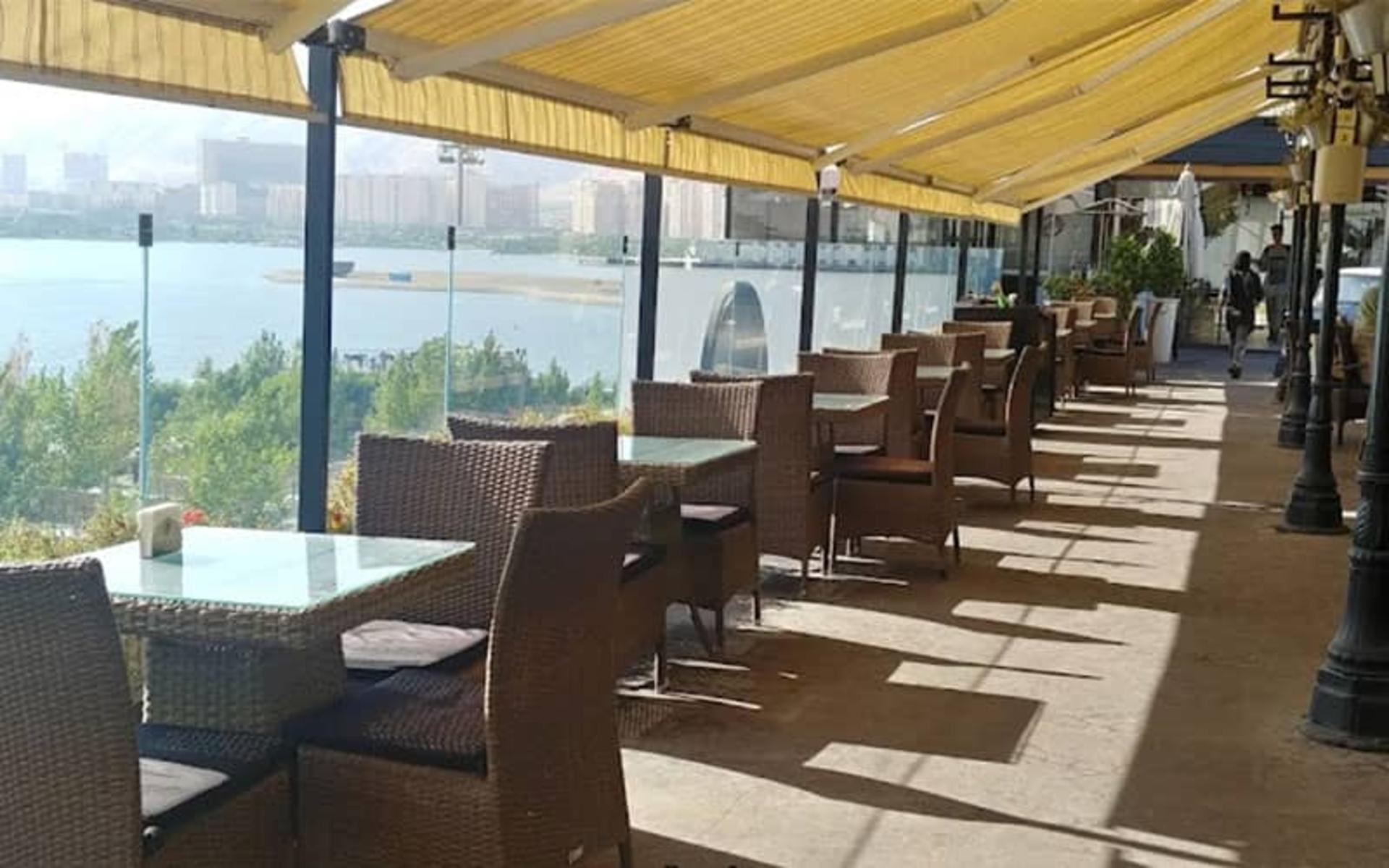 رستوران بزرگی با صندلی های حصیری رو به دریاچه