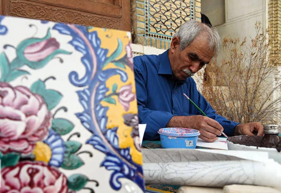 استاد هنرمندی در حال کار روی کاشی هفت رنگ