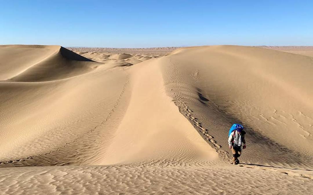 مردی در حال پیاده‌روی در کویر