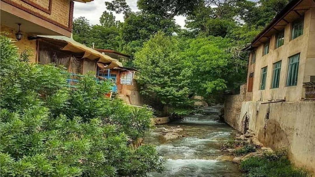 خانه های روستای برغان در جوار رودخانه و بوته های سبز