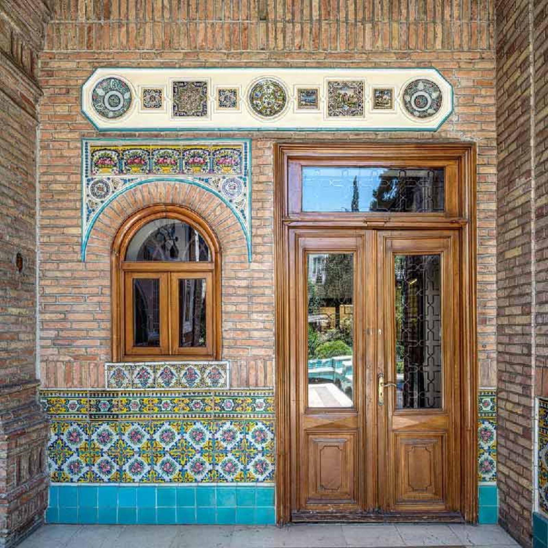 درب‌ و پنجره چوبی و دیوارهای آجری خانه مقدم 