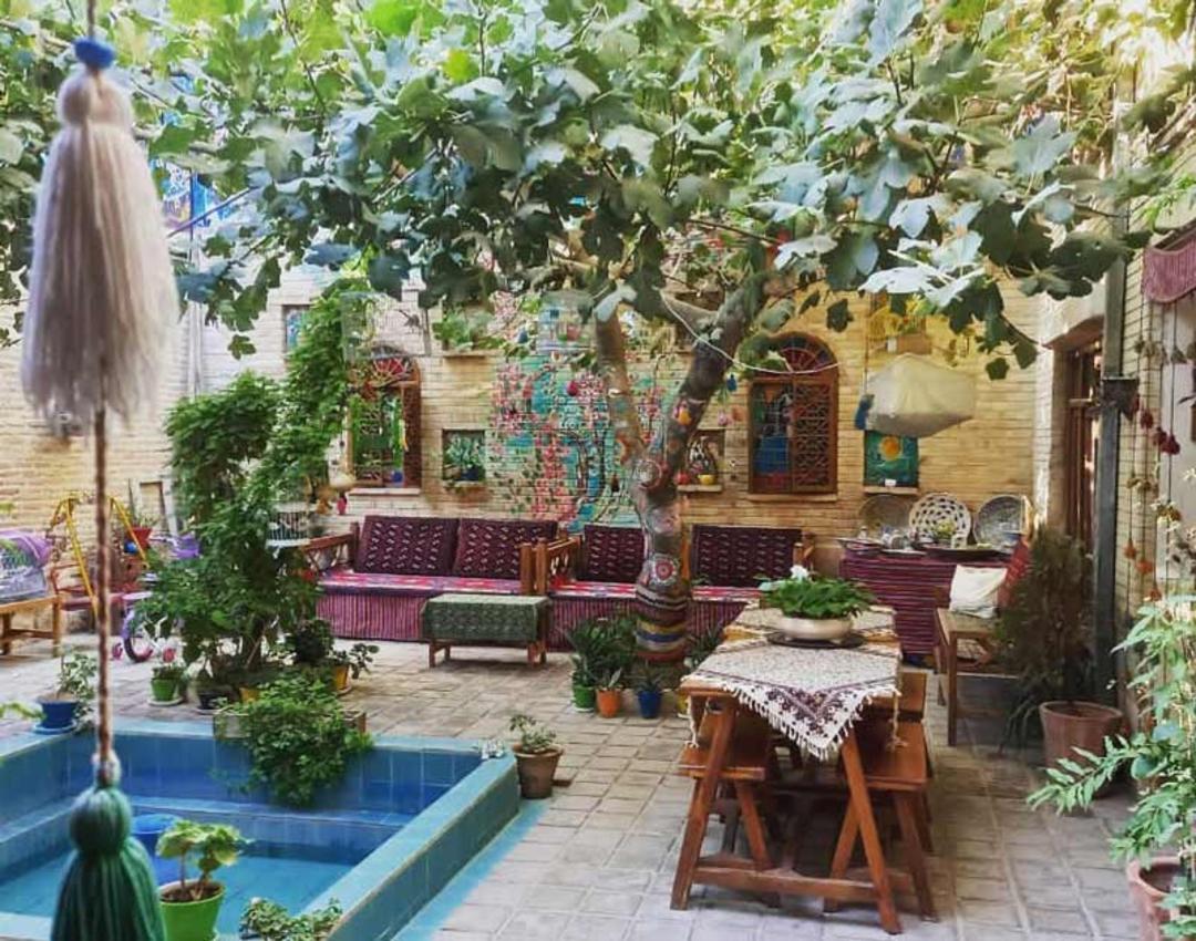 حیاط اقامتگاه بومگردی ماه سلطان با حوض آبی و تخت چوبی