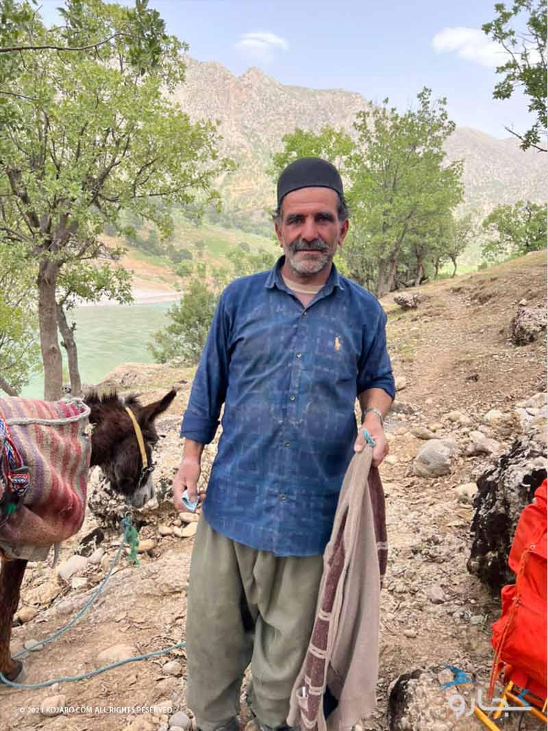 پیرمردی با لباس محلی در کوهستانی کنار رودخانه