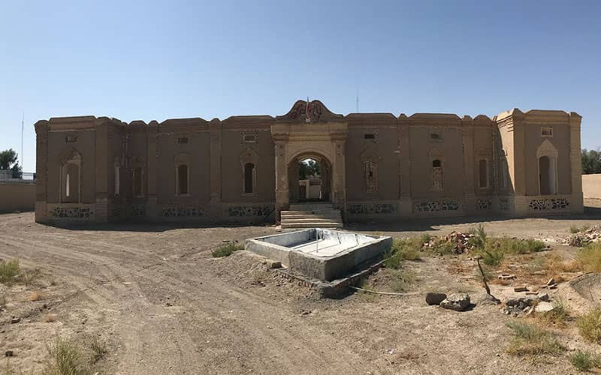 نمای ساختمانی و یک طبقه با حوضی بدون آب در مقابلش
