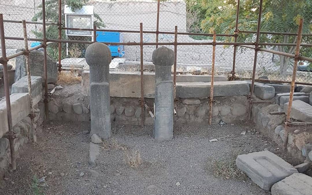 دو ستون سنگی کوتاه و چند قطعه سنگ در محیط دارای فنس