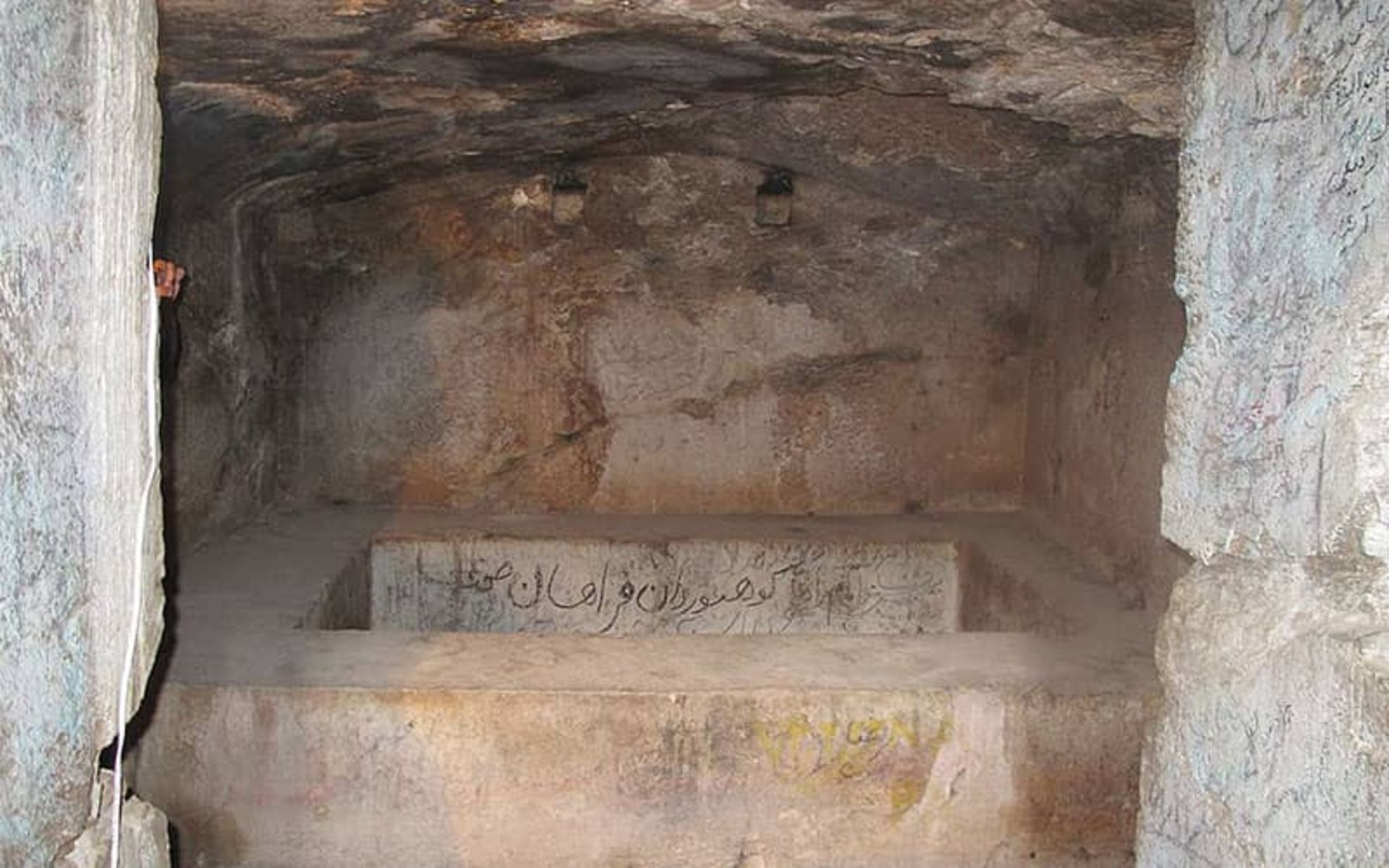 قبری ساده در اتاقی سنگی و قدیمی