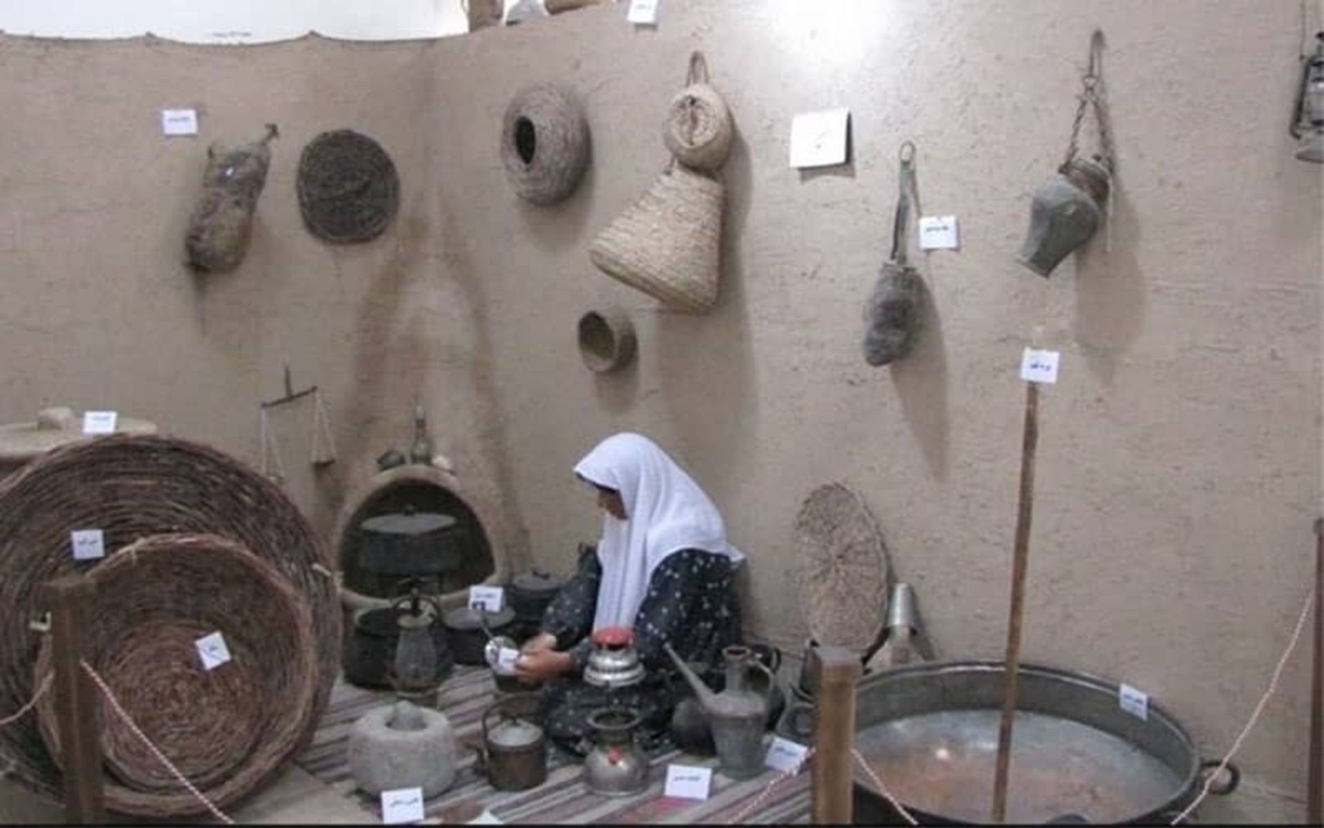 مجسمه زنی در کنار وسایل زندگی روستایی