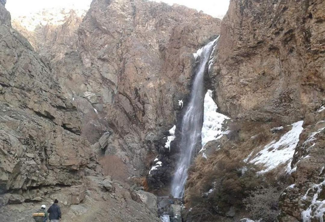 آبشار چال مگس از نمای دور میان صخره های بلند کوهستانی