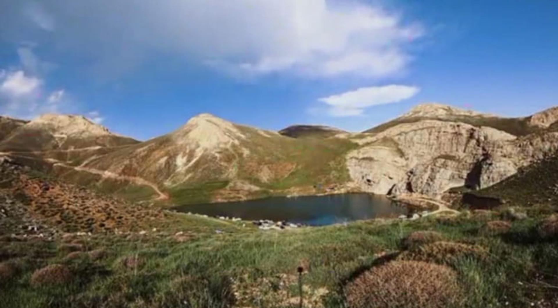 دریاچه لزور زیر آسمان ابری کنار کوهستان از نمای دور