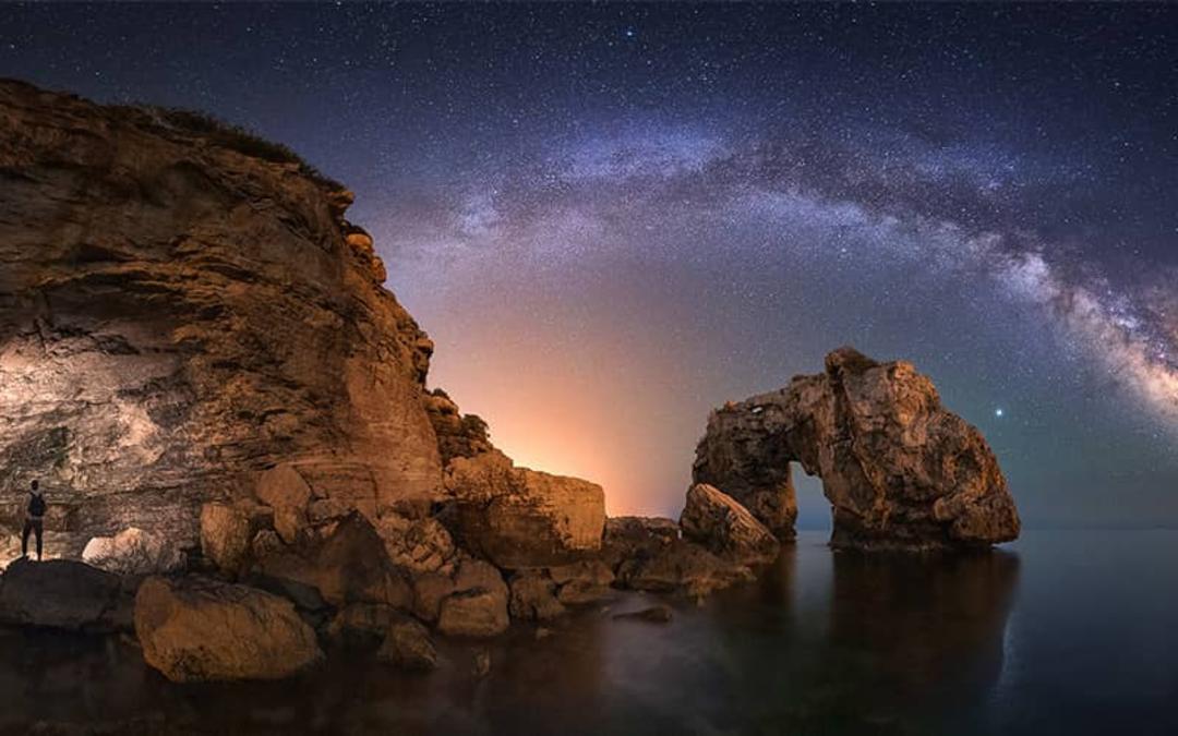 آسمان پرستاره بر فراز صخره های ساحلی
