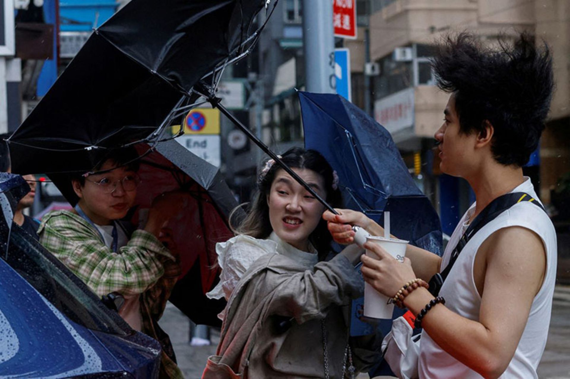 مبارزه عابران با باد برای نگه داشتن چتر در طوفان هنگ کنگ؛ منبع عکس: REUTERS؛ عکاس: Tyrone Siu