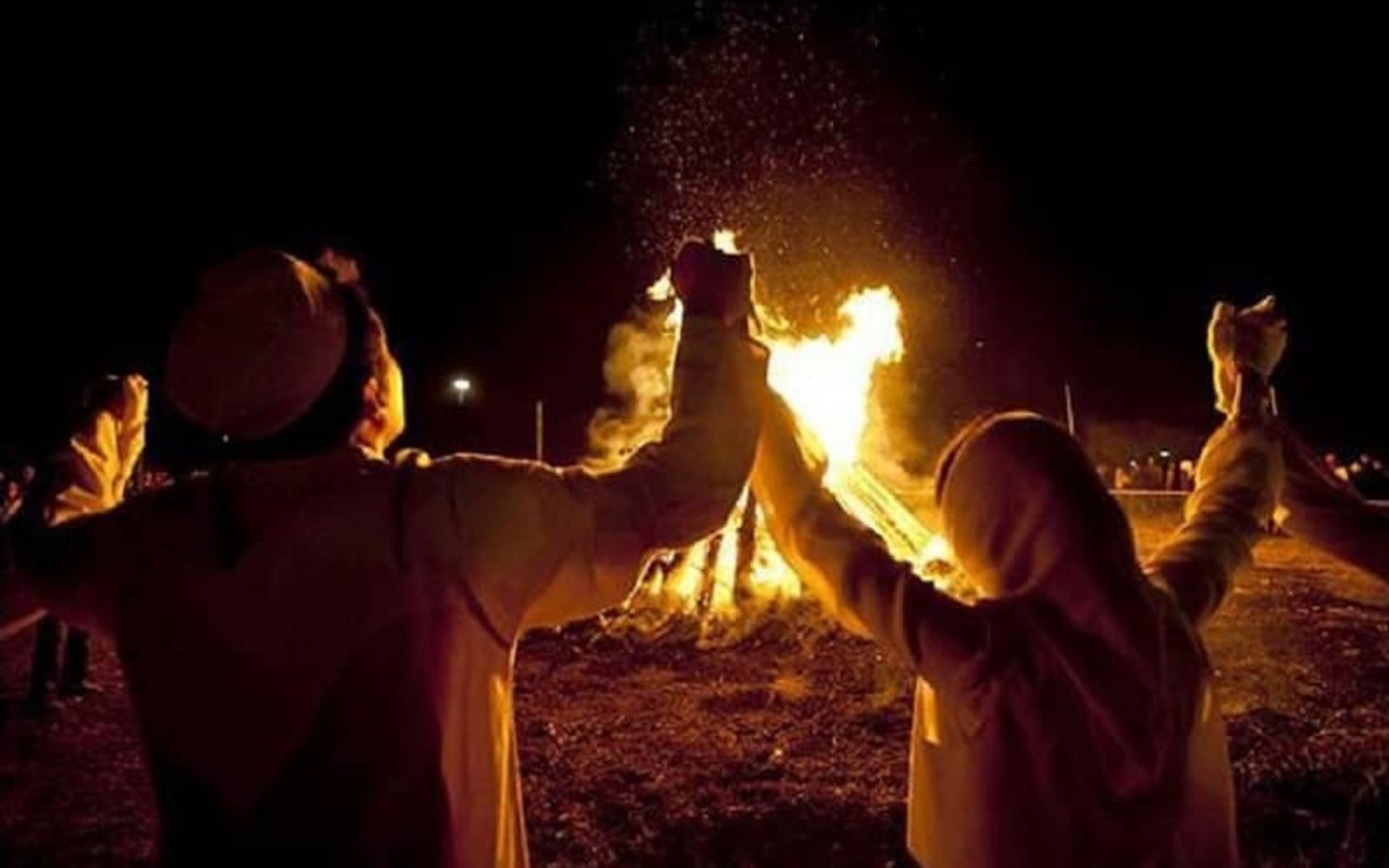 چندین زن و مرد دست در دست هم در کنار آتش چهارشنبه سوری