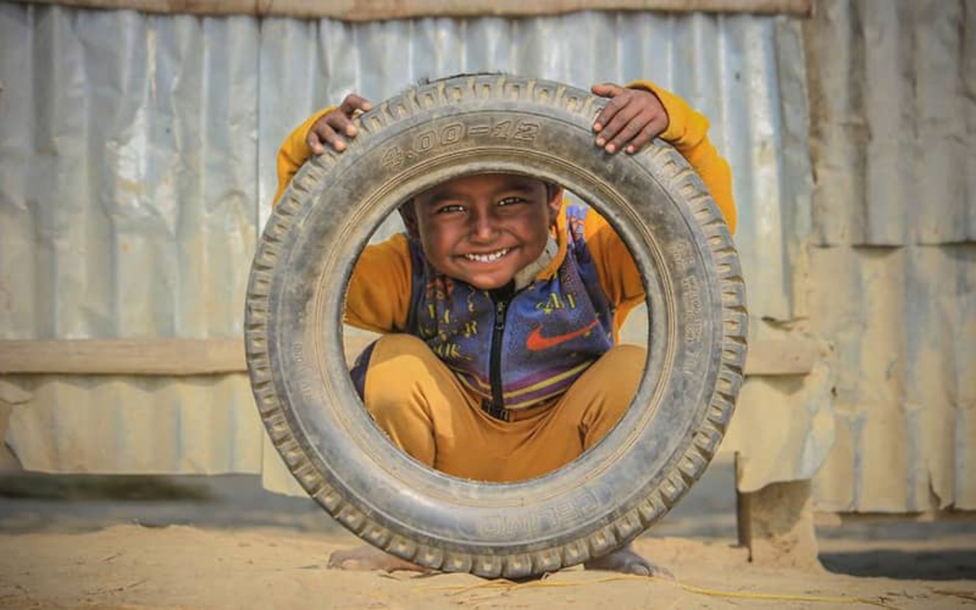 کودکی خندان با لاستیکی در دست