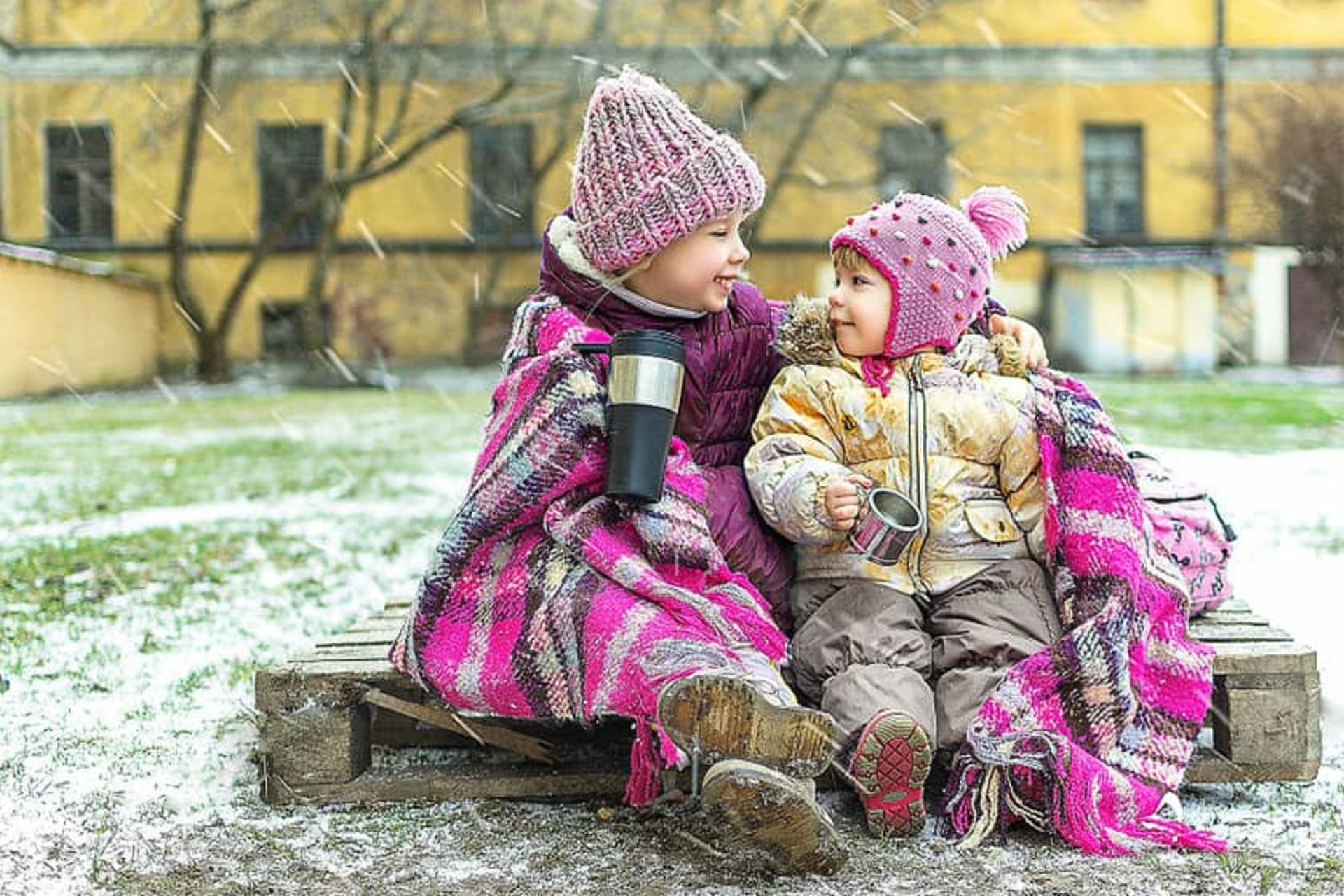 دو کودک با لباس زمستانی در حال لبخند به یکدیگر