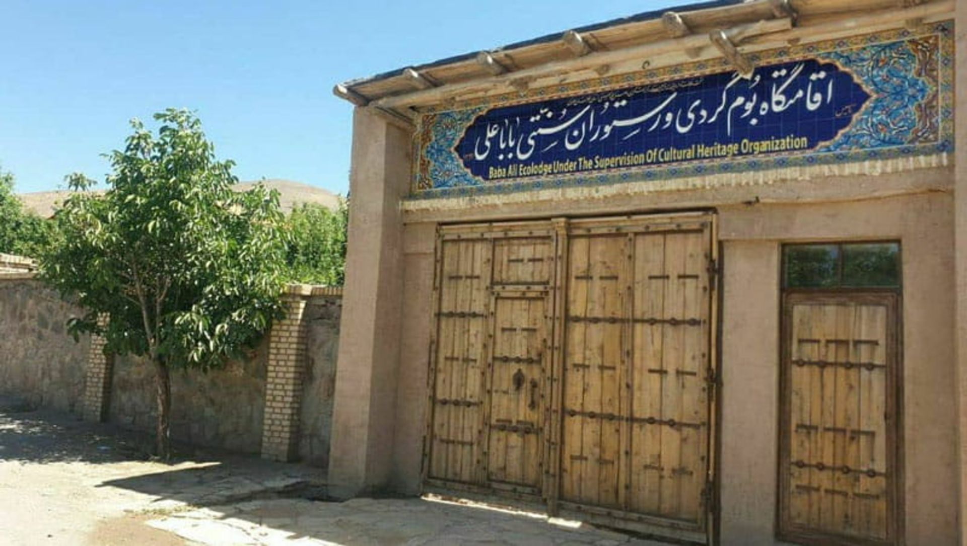 ورودی چوبی اقامتگاه بومگردی و رستوران سنتی باباعلی مشهد