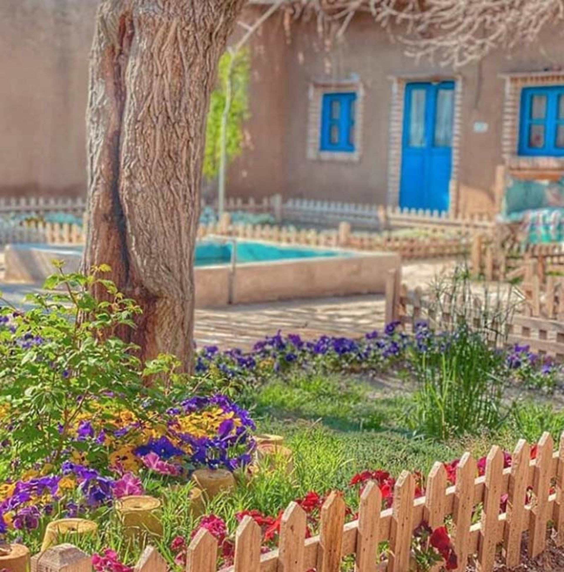 نرده ها چوبی در حیاط سرسبز و پرگل اقامتگاه بومگردی عمارت کوچه باغ
