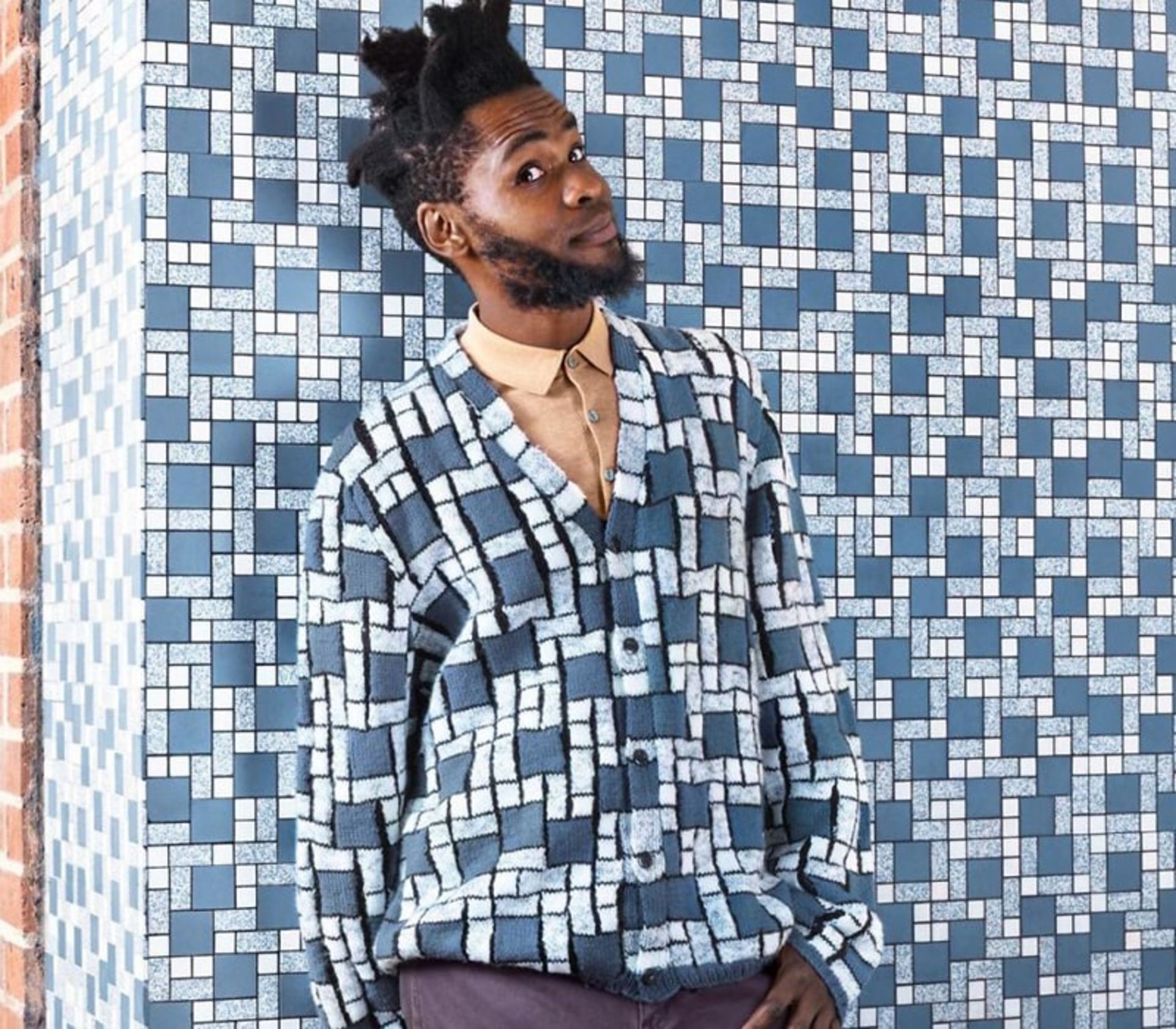 پسری با لباس بافتنی مشابه دیوار کاشی‌کاری