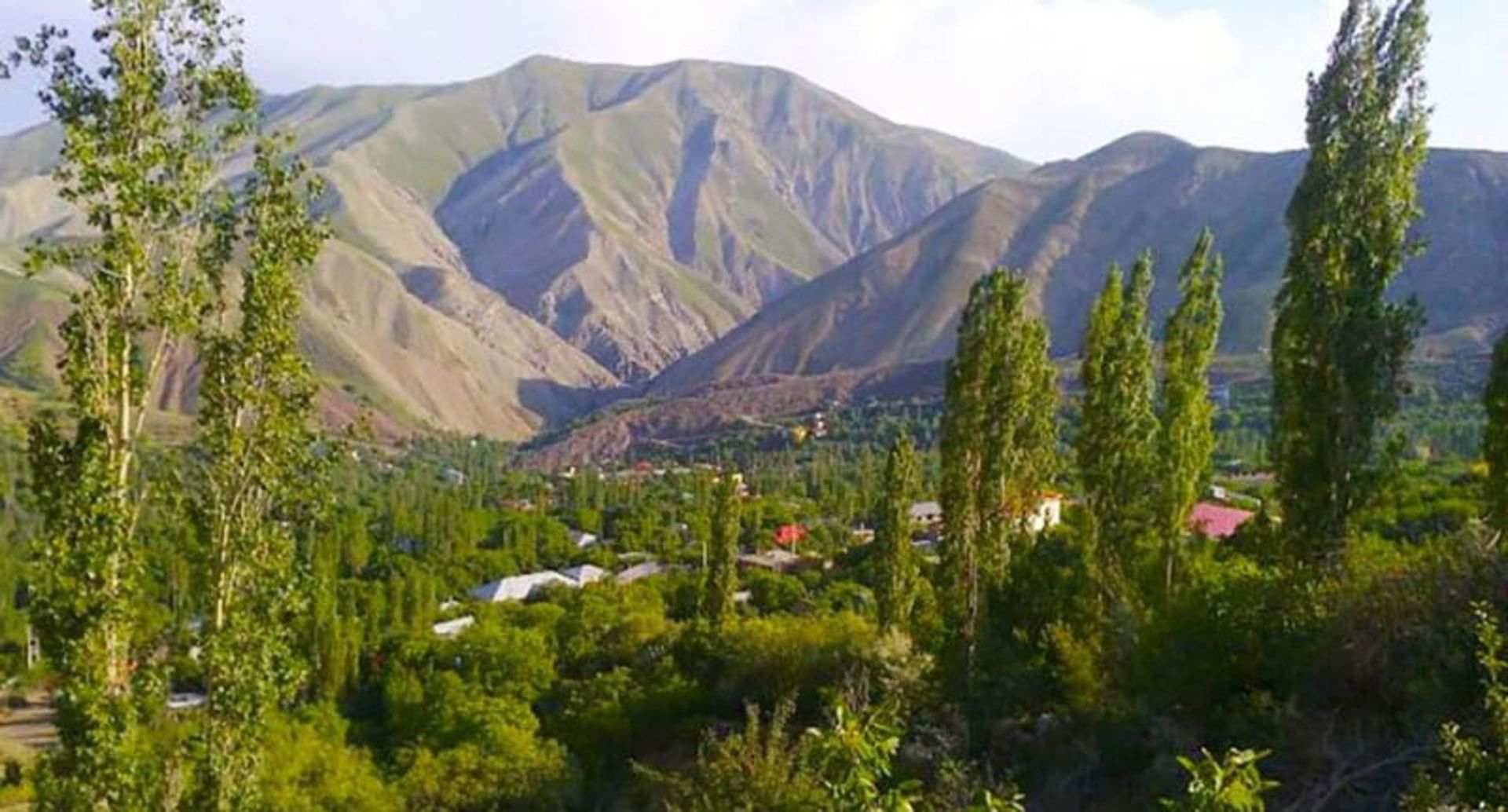 درختان سرسبز و خانه های روستایی در دامنه کوهستان در روستای امامه، ره‌بال آسمان، عکاس نامشخص