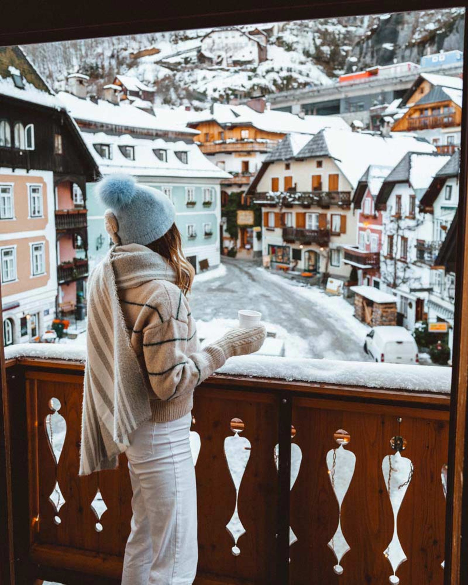 زنی در بالکن خانه‌ای در حال تماشای برف 