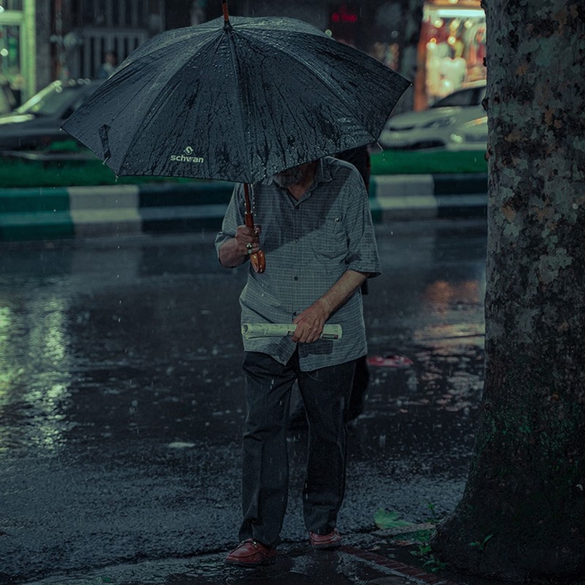 مردی زیر باران در شهر رشت
