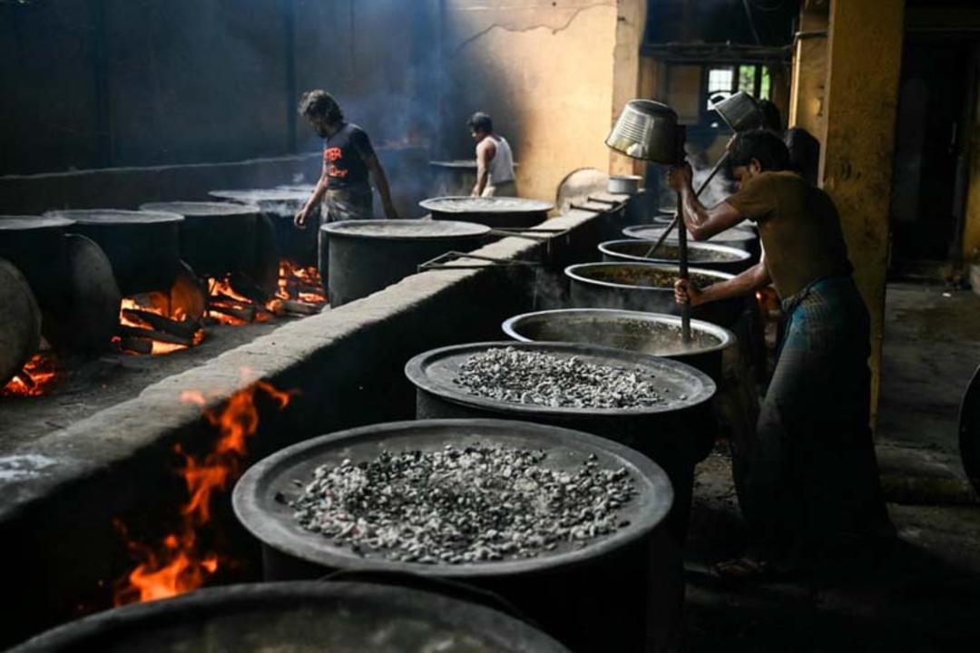 سرآشپزهای هندی برای عید قربان در آشپزخانه ای بزرگ، کاسه های بریانی را هم می زنند