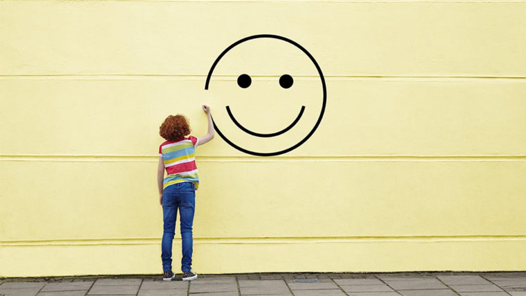 فردی در حال کشیدن لبخند بر دیوار؛ منبع عکس: Harvard Business Review، عکاس: نامشخص