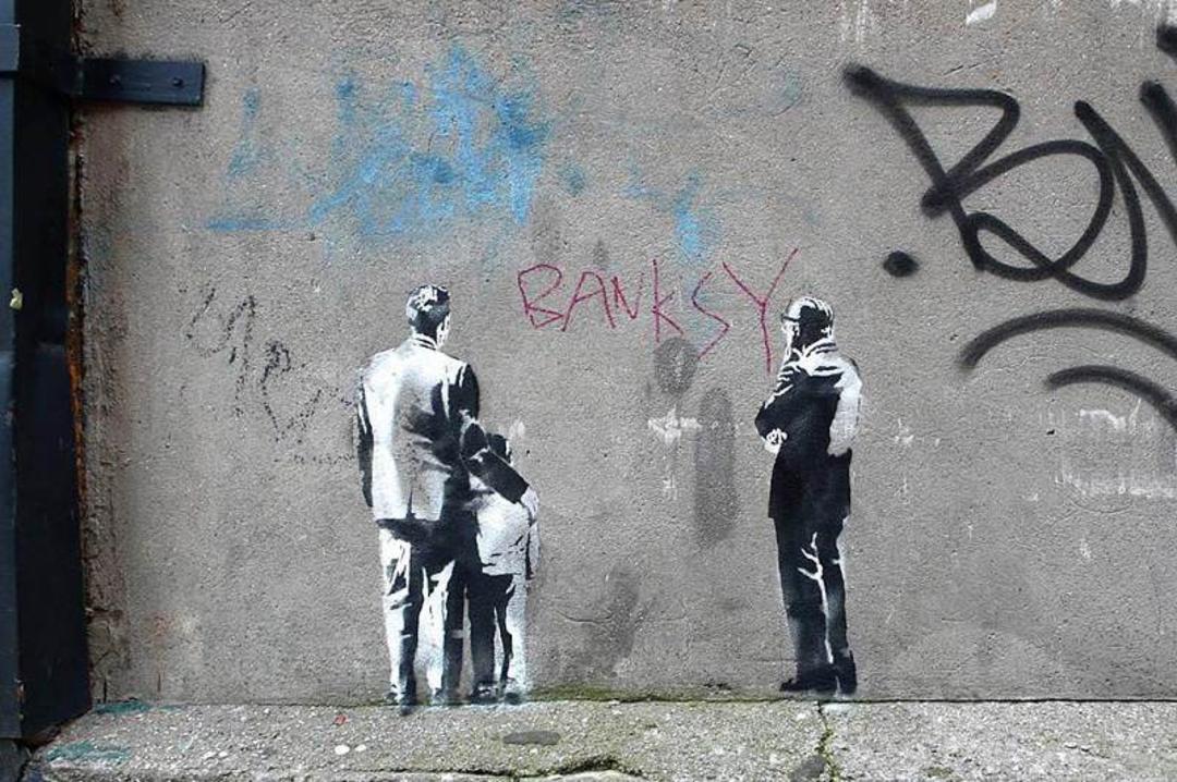 نقاشی دو مرد با یک کودک روی دیوار؛ منبع عکس: وب سایت Banksy.co.uk