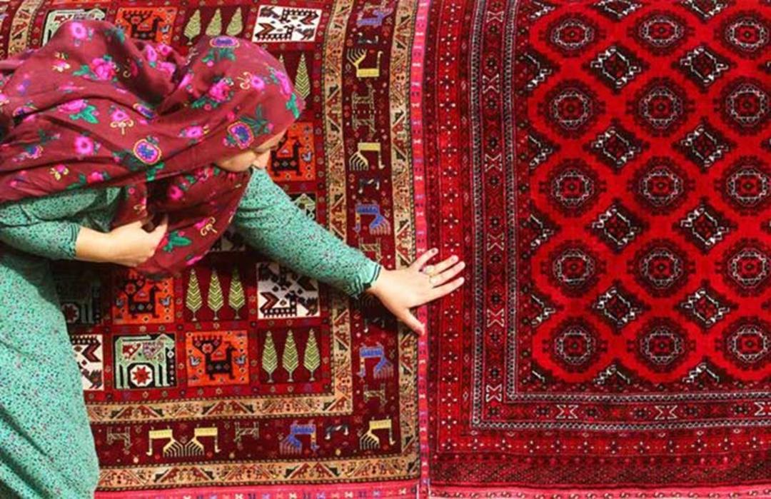 زن ترکمن کنار گلیم؛ منبع عکس: totikala؛ نام عکاس: نامشخص