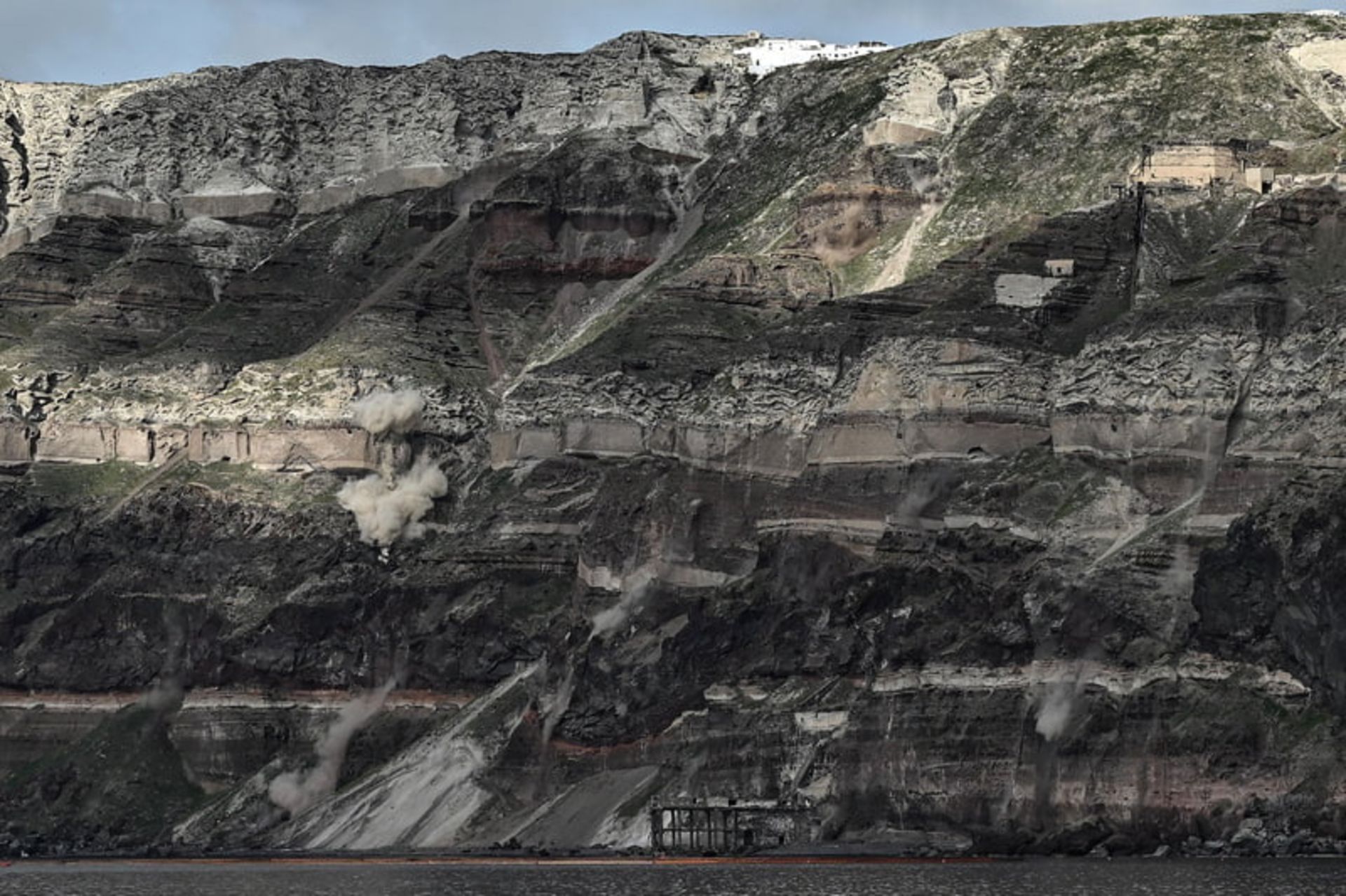  ابرهای گرد و غبار در امتداد یک بخش از صخره‌ های سنگی جزیره سانتورینی پس از زلزله؛ منبع عکس: theguardian؛ نام عکاس:  Aris Messinis