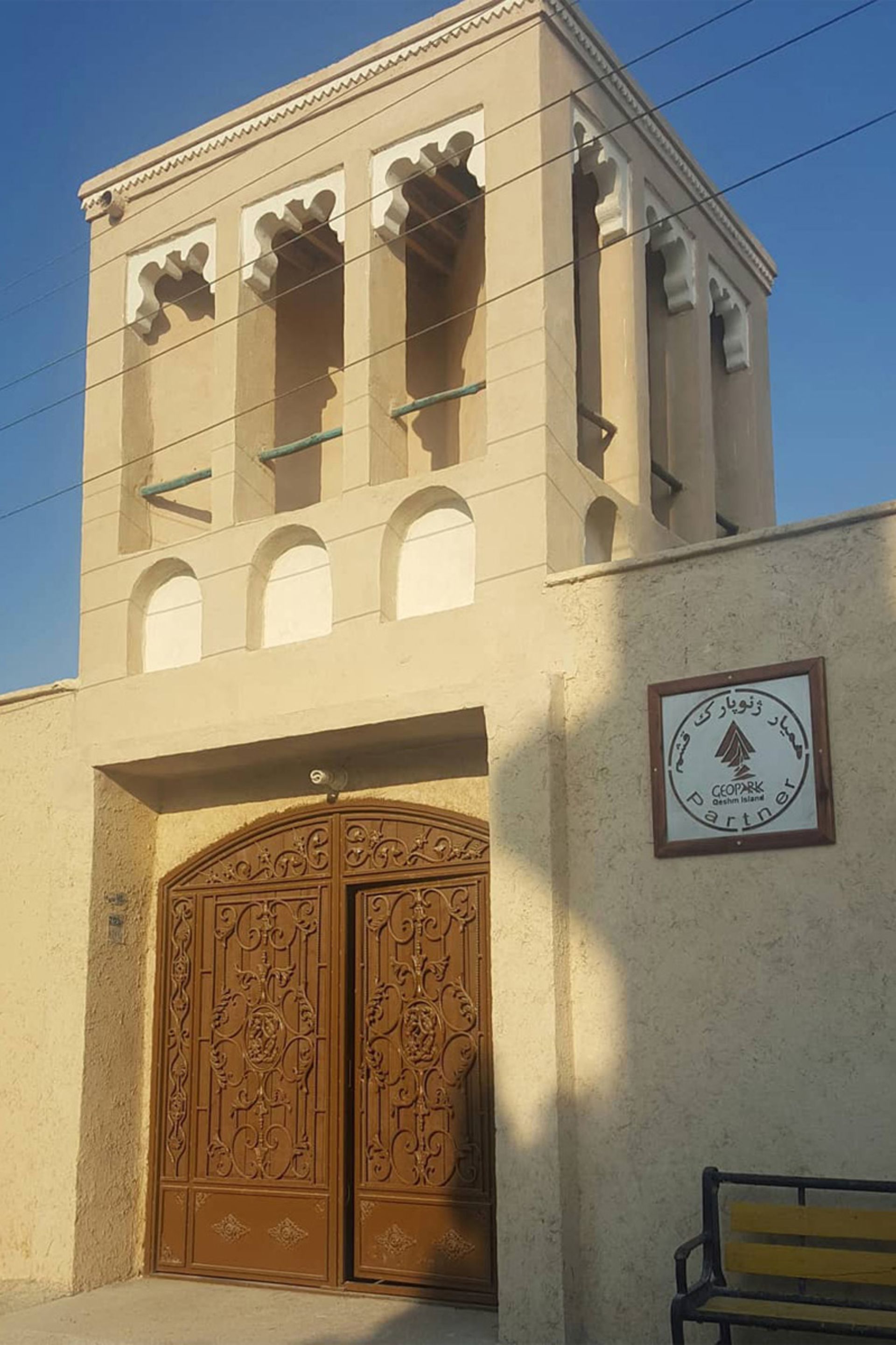 ساختمانی سنتی با بادگیر و درب چوبی کنده‌کاری شده