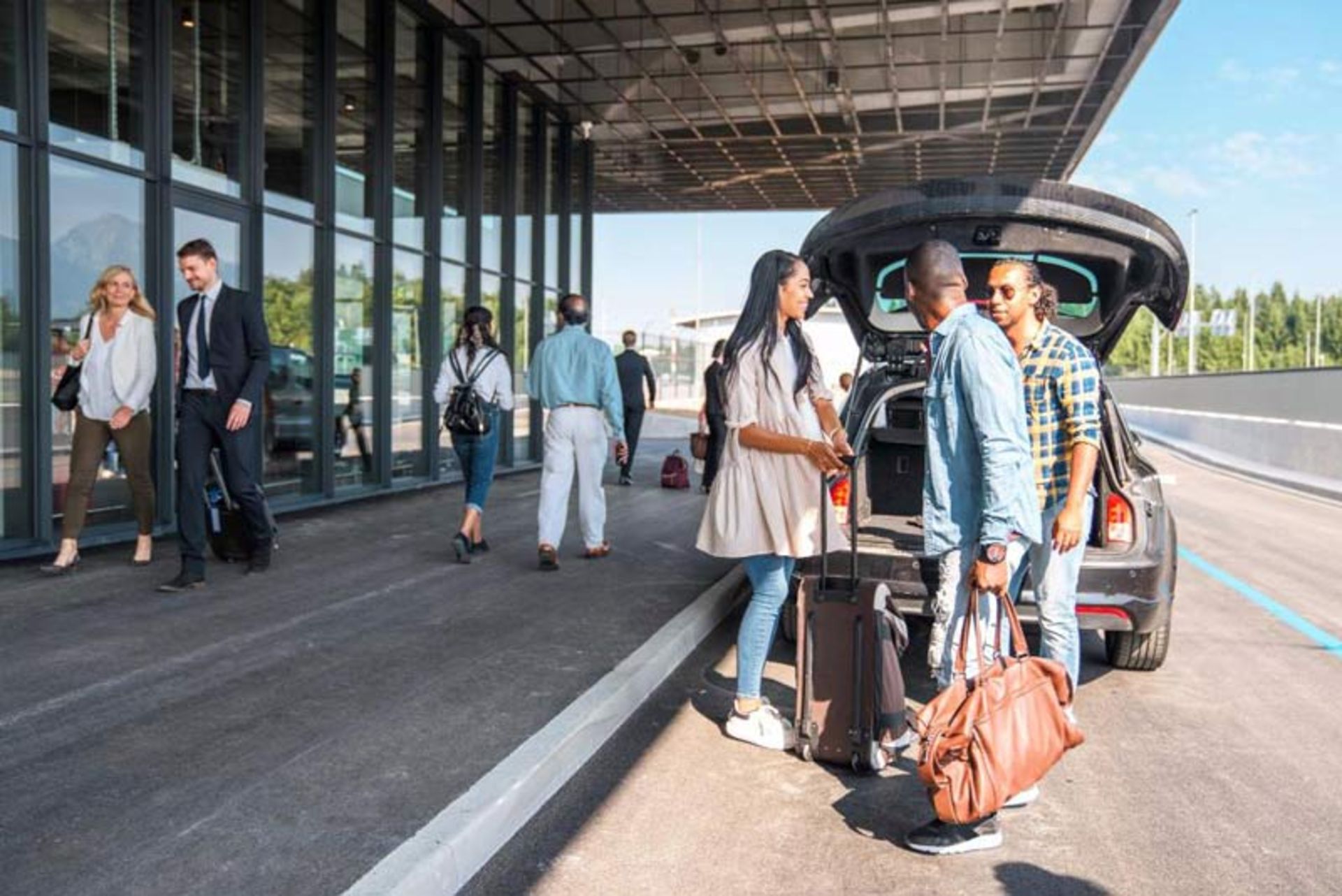 خارج کردن چمدان‌ها از صندوق عقب خودرو در مقابل در ورودی شیشه‌ای و مدرن فرودگاه